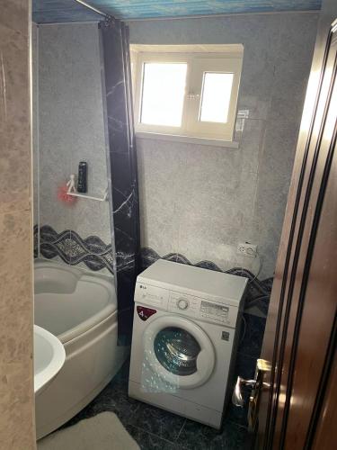 a bathroom with a washing machine and a window at Aile Bukhara in Bukhara