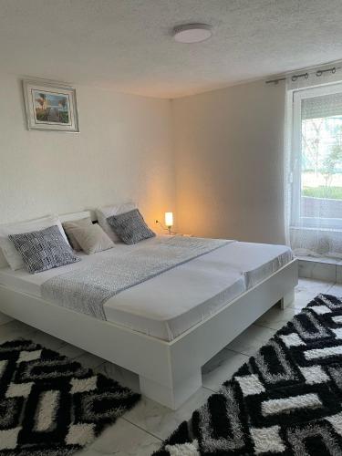 a large white bed in a bedroom with a window at Villa Dzeno Sarajevo in Krivoglavci