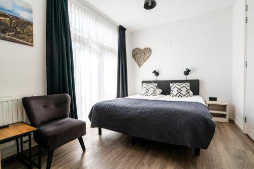 a bedroom with a bed and a chair and a window at Duinhotel Haga in Zoutelande