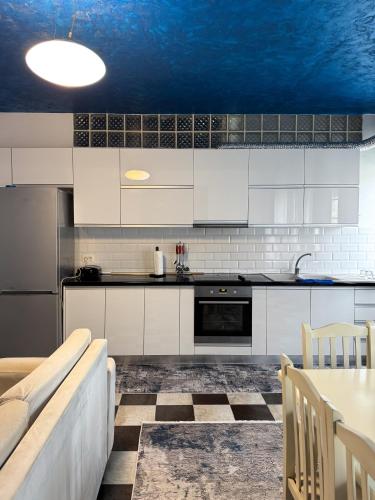 a kitchen with white cabinets and a blue ceiling at Marina Apartment - The Ocean Heart of Shkodra in Shkodër