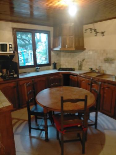 Il comprend une cuisine avec une table et des chaises en bois. dans l'établissement Vivre en garrigue, à Boucoiran-et-Nozières