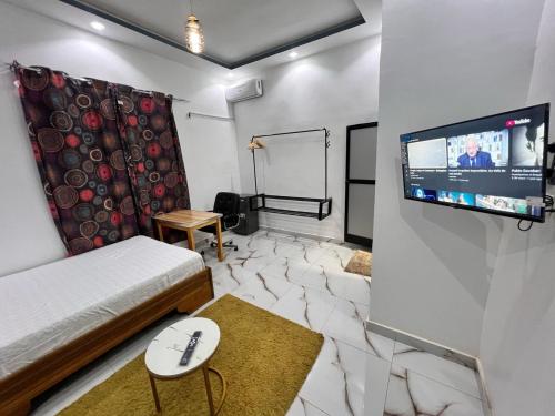 a living room with a bed and a flat screen tv at Résidence Khadija Aéroport AIBD Confort in Rufisque