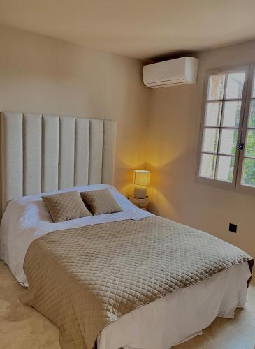 une chambre avec un grand lit avec une grande fenêtre dans l'établissement Appartement calme et rénové, à Gassin