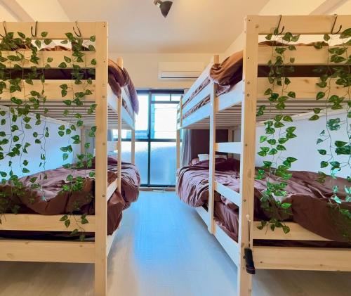 a room with three bunk beds with plants on the walls at ZenAbode, 5-minute walk from Taiko-dori Station, 1-minute train ride from Nagoya Station, excellent location for sightseeing in Nagoya in Nagoya