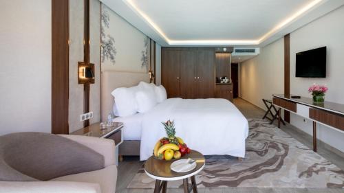 a hotel room with a bed and a table with a bowl of fruit at Savoy Le Grand Hotel Marrakech in Marrakech