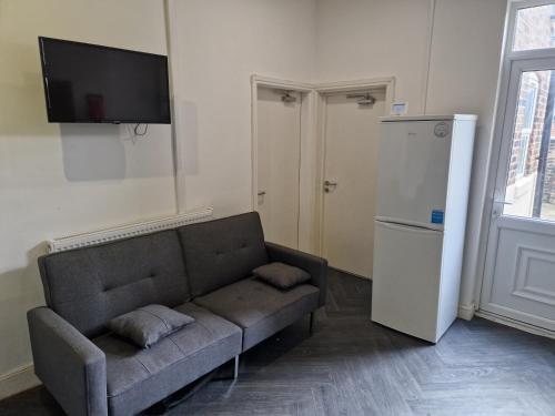 a living room with a couch and a flat screen tv at Shelton Old Road Guest house in Stoke on Trent