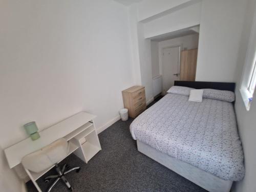 a small bedroom with a bed and a desk at Shelton Old Road Guest house in Stoke on Trent