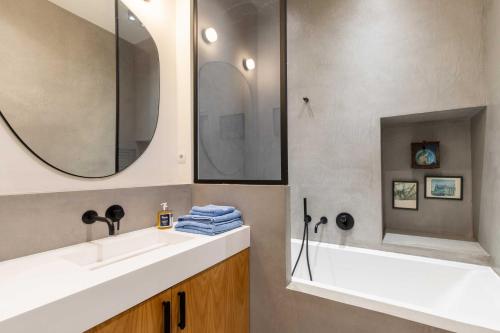 une salle de bain avec un lavabo, une baignoire et un miroir dans l'établissement Comme une maison sur l'Île Saint Louis, à Paris