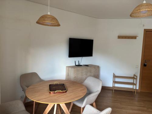 ein Zimmer mit einem Tisch mit Stühlen und einem Fernseher in der Unterkunft TUCA - Apartamento en Vielha in Vielha e Mijaran