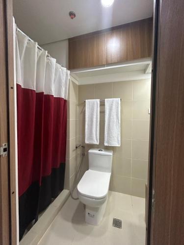 a bathroom with a toilet and a red and white shower curtain at New 1BR Haven Suite Lush Residences Smart TV Netflix Hi speed internet in Manila