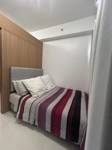 a bedroom with a bed with a striped blanket at New 1BR Haven Suite Lush Residences Smart TV Netflix Hi speed internet in Manila