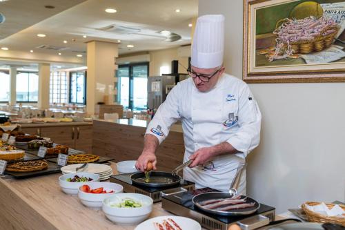 een chef-kok die eten bereidt op een bar in een restaurant bij Hotel Rio Bellaria in Bellaria-Igea Marina