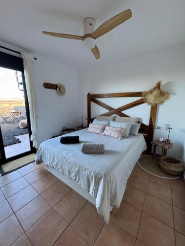 a bedroom with a bed with a ceiling fan at Villa Miraki Fuerteventura Surf Relax in La Oliva