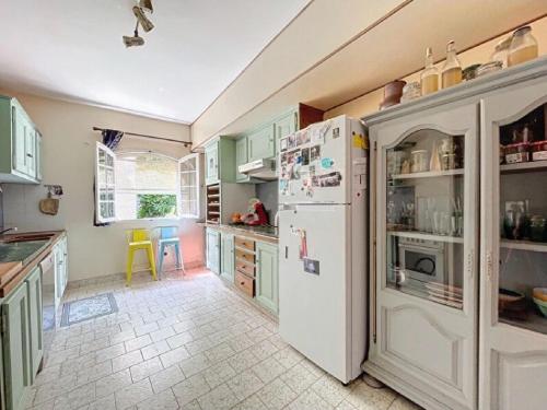 a kitchen with a white refrigerator and a table at Maison de famille en Provence in Rognes