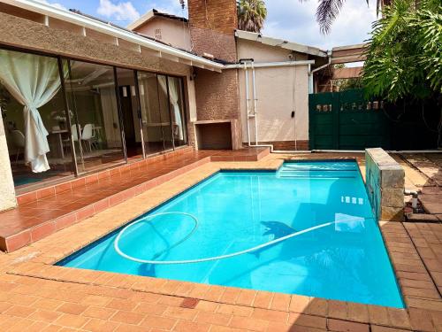 a large blue swimming pool in front of a house at Cozy Home with Pool, Braai & Top Security in Kempton Park