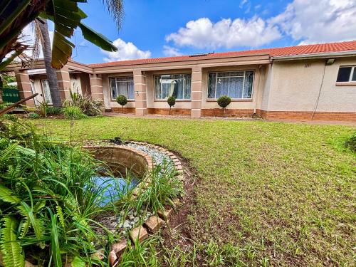 a house with a pond in front of a yard at Cozy Home with Pool, Braai & Top Security in Kempton Park