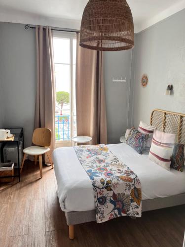 a bedroom with a bed and a window at Hôtel Eden - La Baigneuse in Juan-les-Pins