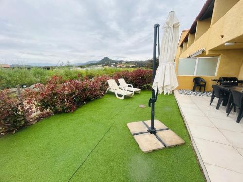un patio avec une pelouse avec un parasol et des chaises dans l'établissement La belle vie F4 bord de plage avec jardin, à Calcatoggio