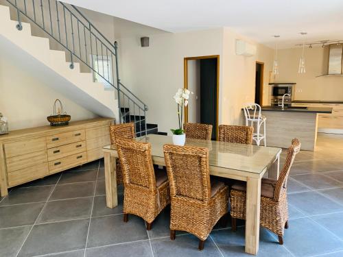 une salle à manger avec une table en bois et des chaises en osier dans l'établissement Le mas des oliviers, à Sanary-sur-Mer