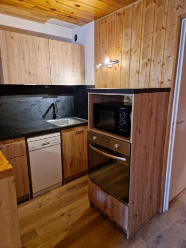 La cuisine est équipée de placards en bois, d'un évier et d'un four micro-ondes. dans l'établissement Duplex 59m2 - proche centre - balcon plein sud, à Corrençon-en-Vercors