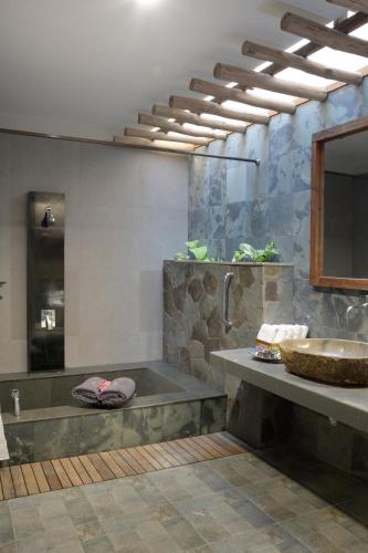 a bathroom with a large tub and a sink at WARISAN Heritage Boutique Hotel in Solo