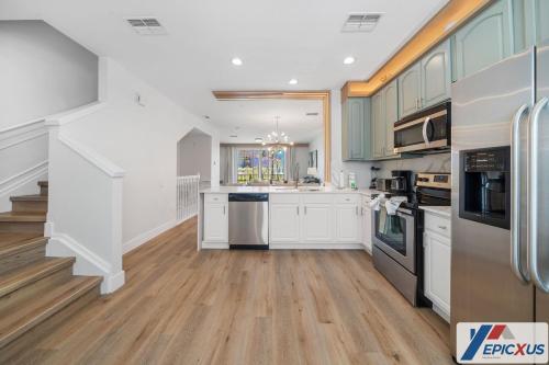 a kitchen with white cabinets and wooden floors at The Epic Toronto Vista Cay Orlando in Orlando