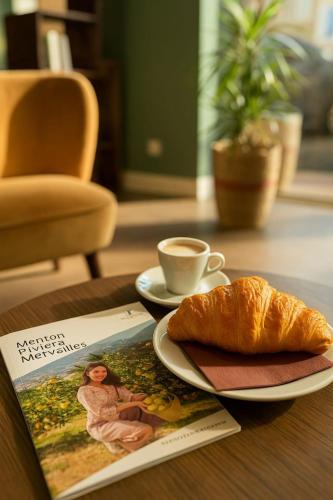a table with a plate of bread and a cup of coffee at Hotel Parisien in Menton