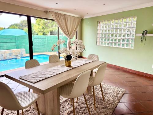 a dining room with a table and chairs and a pool at Cozy Home with Pool, Braai & Top Security in Kempton Park