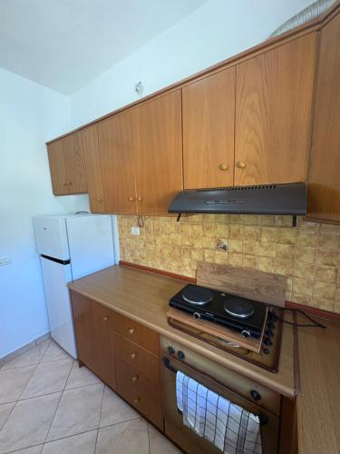 a kitchen with wooden cabinets and a stove top oven at Olga's apartment Drymades in Dhërmi
