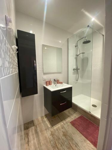 une salle de bain blanche avec un lavabo et une douche dans l'établissement Bright apartment in the historic center, à Marseillan