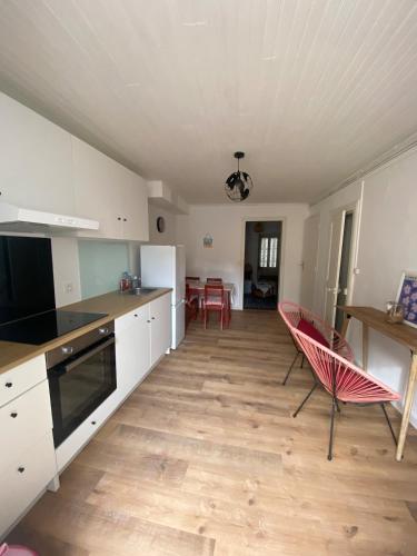- une cuisine avec des placards blancs et des chaises rouges dans l'établissement Bright apartment in the historic center, à Marseillan