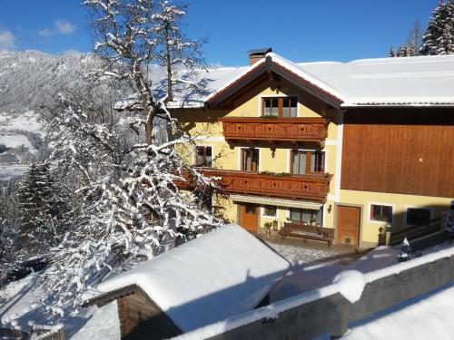 ein Haus im Schnee mit einem schneebedeckten Baum in der Unterkunft Haus Oberstocker in St. Johann im Pongau