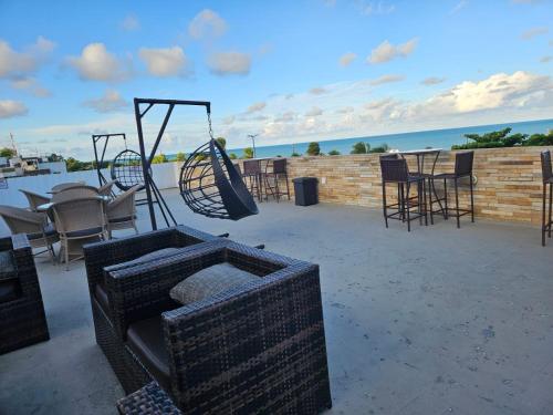 a patio with a swing and tables and chairs at Apto 515 - Seu Refúgio na Praia - Nobile Hotel in João Pessoa