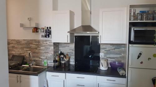 une cuisine avec des armoires blanches et un comptoir noir dans l'établissement Charming 2-room apartment in Saint Jean d'Angely district, à Nice