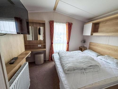 a small bedroom with a bed and a window at Lovely 6 Berth Caravan At Caldecott Hall Country Park, Norfolk Ref 91010C in Great Yarmouth