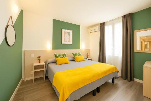 a bedroom with a bed with yellow and green walls at Hotel Parisien in Menton