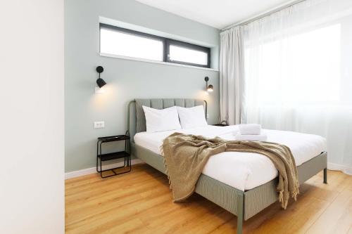 a bedroom with a bed with white sheets and a window at Yellow - 3 Bedroom House with Private Garden, 10 mins driving from Old Town in Braşov