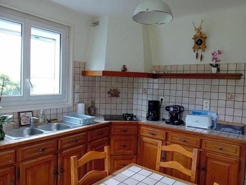 une cuisine avec des armoires en bois, un évier et une fenêtre dans l'établissement Gîte Saint-Jean-pied-de-Port Chez PASCALINE, à Ispoure