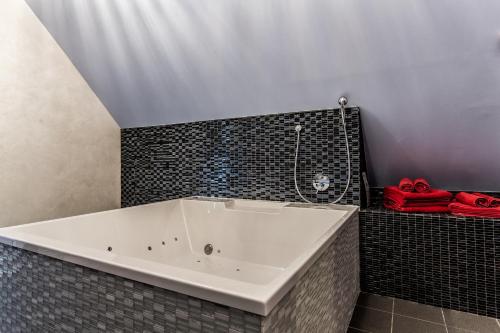 a white bath tub in a bathroom with red towels at Lustra Stundenhotel - Adults Only in Landshut