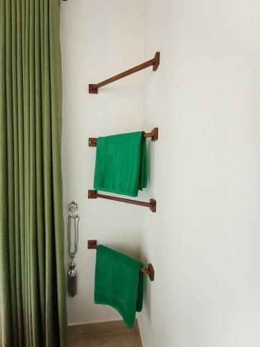 a bathroom with green towels hanging on a wall at Rainforest Nest in Deniyaya