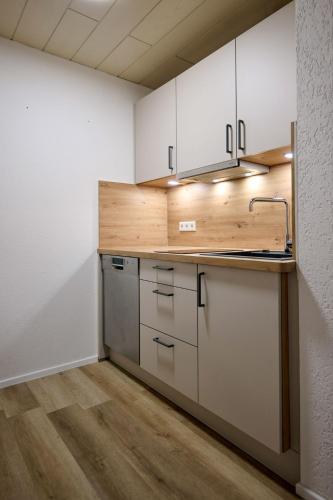 a kitchen with white cabinets and a wooden counter top at Ferienwohnung Kuhn in Wallbach