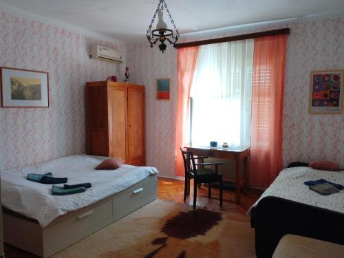 a bedroom with two beds and a desk and a window at Kuća za odmor u Banatu in Debeljača