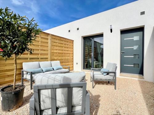une terrasse avec 2 chaises, une table et un arbre dans l'établissement Les Jasmins - 2 Appartements cosy, CLIM, Terrasse, 5 lits, 2 SDB, 8 personnes, à Fos-sur-Mer