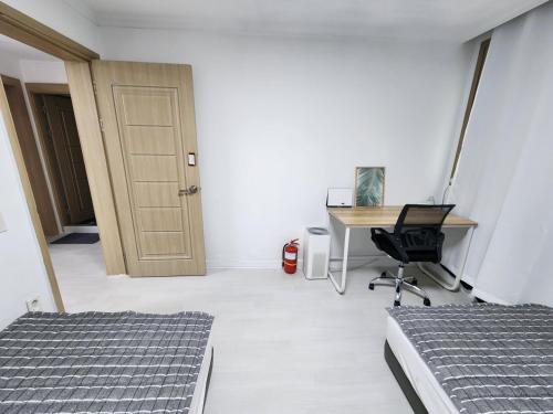 a room with two beds and a desk with a computer at Stay JAYU in Daejeon