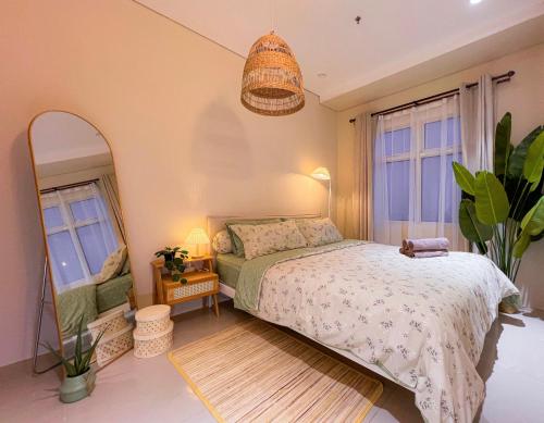 a bedroom with a bed and a mirror and a lamp at Madison Park Apartment HOMEY by Host Jess in Jakarta