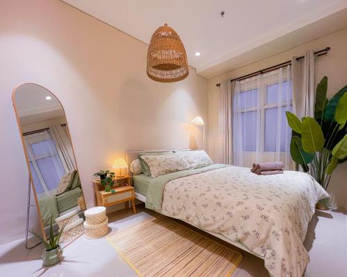 a bedroom with a bed and a mirror at Madison Park Apartment HOMEY by Host Jess in Jakarta