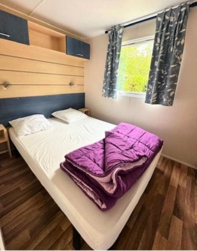 - une chambre avec un lit doté de draps violets et une fenêtre dans l'établissement Camping paradis de la plage, à Saint-Cirq-Lapopie