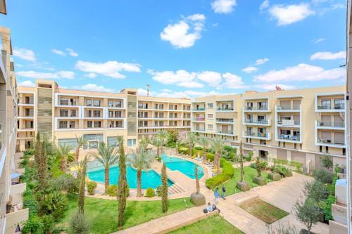 an apartment complex with a swimming pool and palm trees at Royal Deluxe Silver - Marrakech, Luxe Pool View in Marrakech