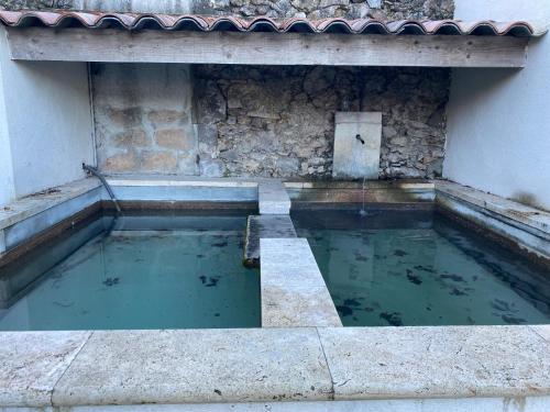 une piscine d'eau à côté d'un bâtiment dans l'établissement Charmant appartement au calme avec grand jardin au pied des remparts, à Brignoles