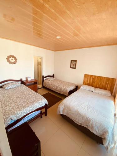 a bedroom with two beds and a wooden ceiling at Alojamiento campestre CASA GRANDE Guateque Hospedaje in Guateque